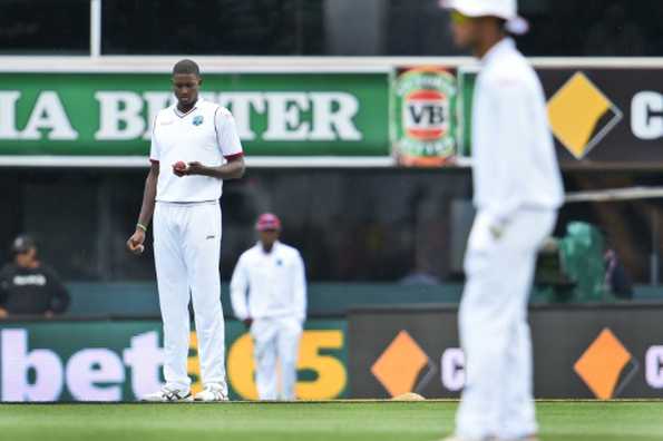 West Indies captain Jason Holder looks at the ball while bowling to Australia on the second day of the first cricket Test match in Hobart on December 11, 2015