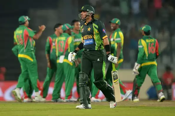 Pakistani captain Misbah-ul-Haq reacts while walking back to the dressing room as Bangladeshi cricketers celebrate his wicket.