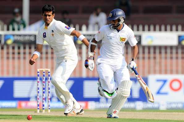 Dimuth Karunaratne runs between the wickets as Mohammad Talha reacts.