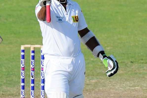 Dilruwan Perera raises his bat in celebration after scoring a half-century.