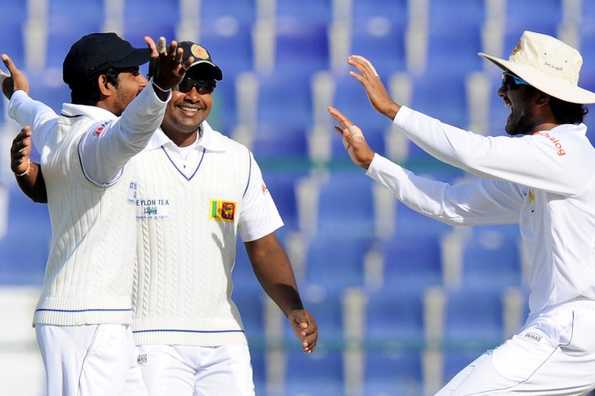 Kaushal Silva (L), celebrates with teammates Rangana Herath (C) and Dinesh Chandimal (R) after his superb catch to dismiss Asad Shafiq.